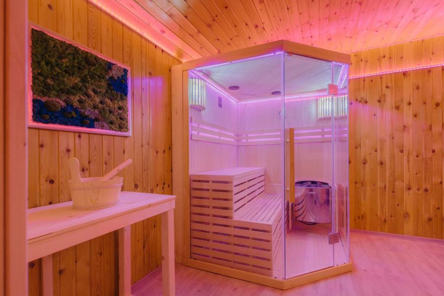 Prosklená sauna s dřevěnými lavicemi a barevným osvětlením